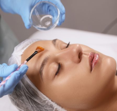 Cosmetologist,Applying,Chemical,Peel,Product,On,Client's,Face,In,Salon